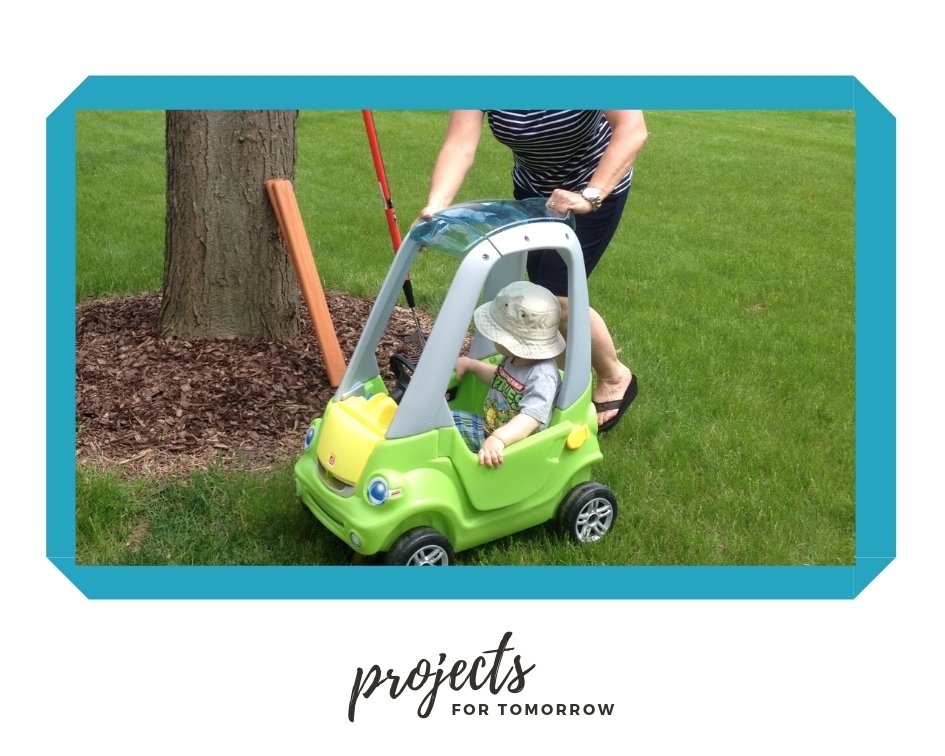 child being pushed in a small car by an adult